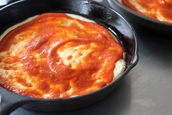 Pizza dough with sauce on top in pan 