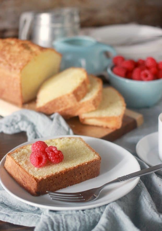 A slice of pound cake on a plate with fresh raspberries
