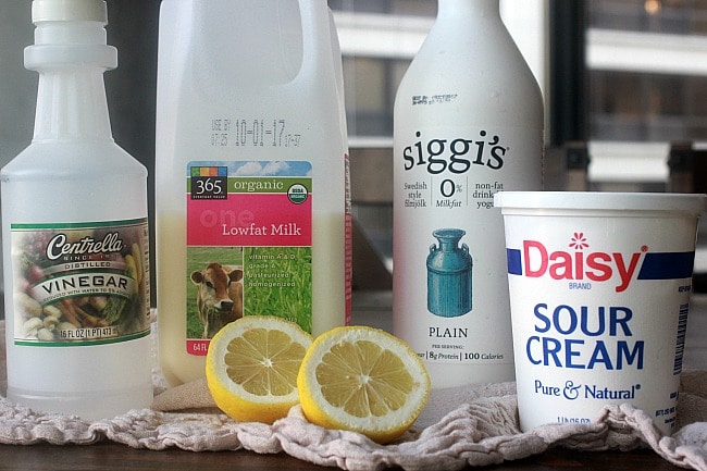 A bottle of vinegar, milk, yogurt, sour cream and a lemon