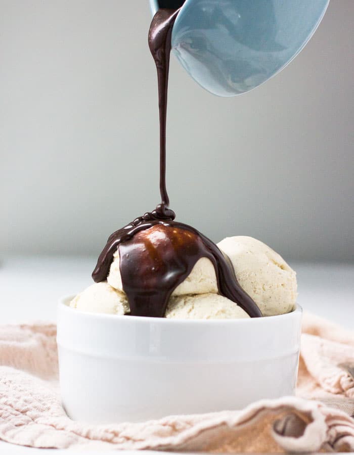 Hot fudge sauce being poured on ice cream